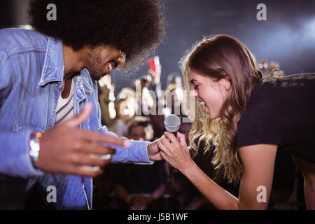 Cheerful woman singing with male singer at nightclub during music festival Stock Photo