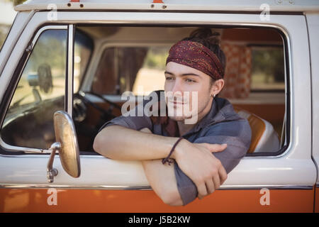 Thoughtful young man looking away while sitting in van Stock Photo
