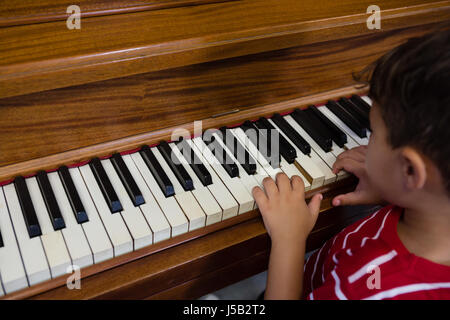 Close up of boy playing piano in classroom at school Stock Photo