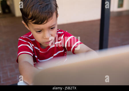 Close up of boy using laptop computer while sitting on chair at school Stock Photo
