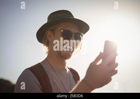 Smiling young man using phone against sky Stock Photo
