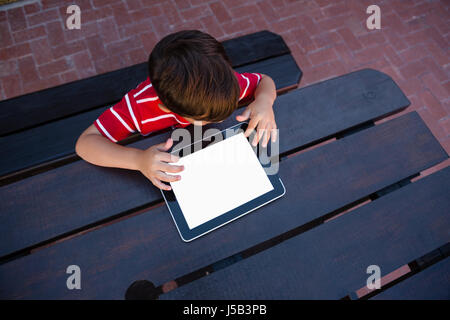 Directly above shot of boy using digital tablet while sitting at table in school Stock Photo