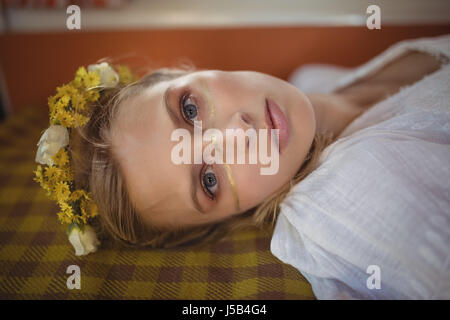 Portrait of young woman wearing flowers lying down in van