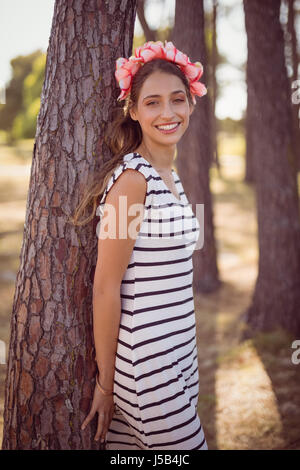 Portrait of smiling young woman leaning on tree in forest Stock Photo