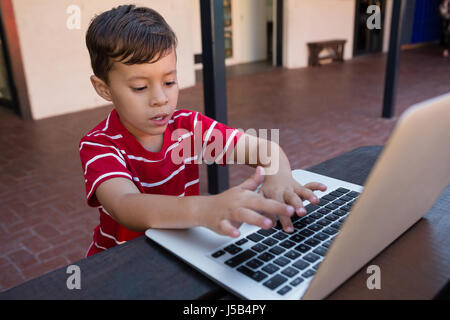 High agle view of boy using digital laptop while sitting at table in school Stock Photo