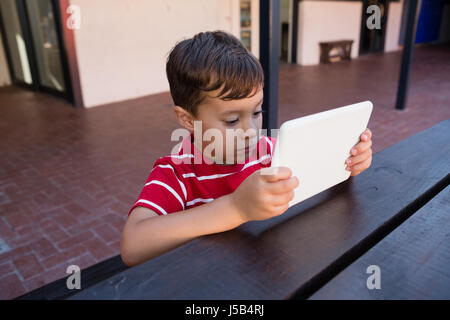 Close up of cute boy using digital laptop while sitting at table in school Stock Photo