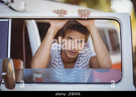 Portrait of serious young man leaning on van at forest Stock Photo