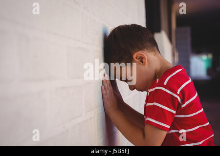 Side view of boy leaning on wall at school