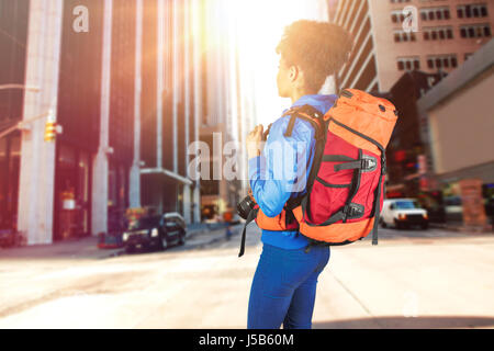 Full length of hiker standing with camera and backpack against new york street Stock Photo