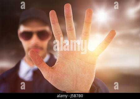 Confident security officer making stop gesture against open road Stock Photo