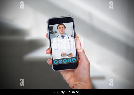 Hand holding mobile phone against white background against sterile bedroom Stock Photo