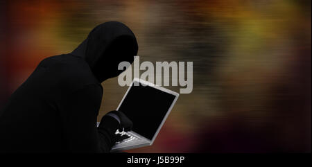 Hacker using laptop against dark background Stock Photo
