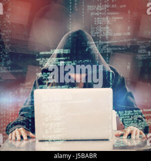 Female hacker sitting by laptop on table  against abstract room Stock Photo