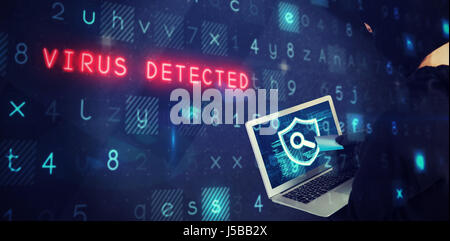 Hacker using laptop and debit card against abstract black room Stock Photo