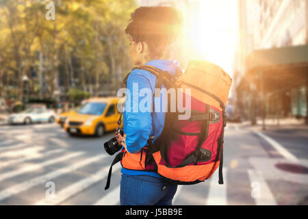 Young woman with backpack holding camera against new york street Stock Photo