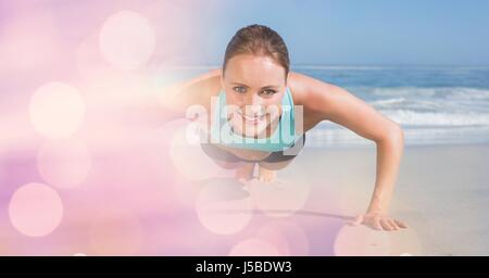 Digital composite of Confident woman doing push ups at beach Stock Photo