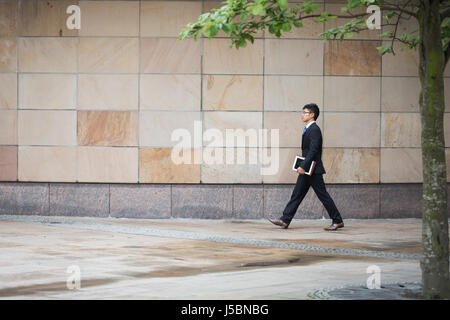 Portrait of a confident asian businessman walking in the city. Stock Photo