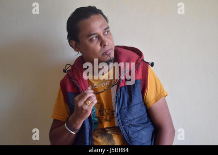 Young man with eyeglasses in hand and mouth, Pune, Maharashtra Stock Photo