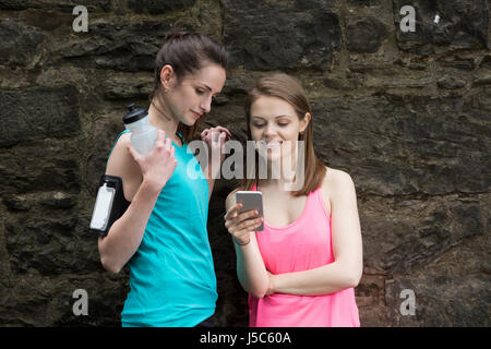 Two female runners sharing information on there smartphone after going for a run.  Action and healthy lifestyle concept. Stock Photo