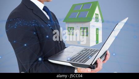 Digital composite of Midsection of businessman holding laptop against 3d house Stock Photo