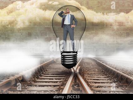 Digital composite of Businessman in light bulb over tracks Stock Photo