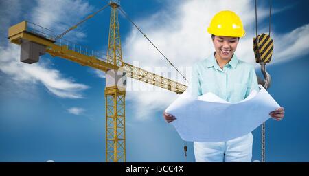Digital composite of Female architect holding blueprint against crane Stock Photo