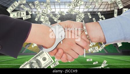 Digital composite of Business people with handcuffs shaking hands at football stadium representing corruption Stock Photo