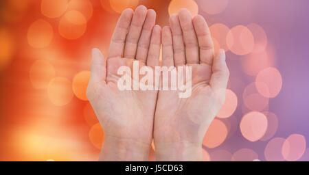 Digital composite of Close-up of cupped hands against glowing bokeh Stock Photo