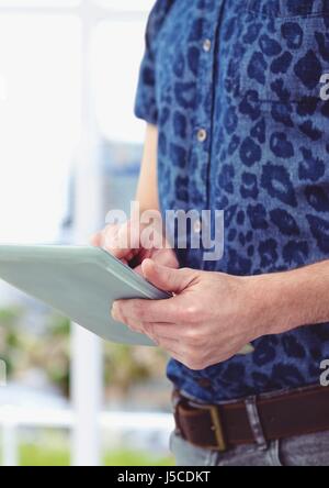 Digital composite of Midsection of male hipster using digital tablet against blurred background Stock Photo