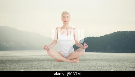 Digital composite of Double exposure of woman meditating over lake Stock Photo