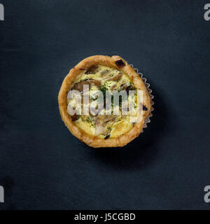 Above view of a homemade mushroom quiche on black slate. Stock Photo