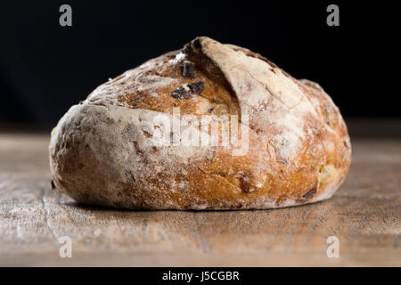 Side view of a rustic loaf of bread on an old wooden table. Stock Photo