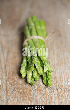 A bunch of fresh asparagus sitting on a rustic wooden table. Stock Photo