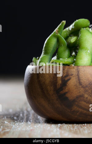 Bowl of edamame sitting on a rustic wooden table. Stock Photo