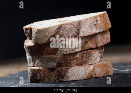 Slices of rustic bread on an old wooden table. Stock Photo
