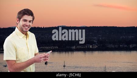 Digital composite of Portrait of man using mobile phone against lake Stock Photo