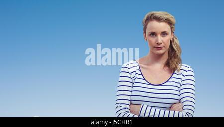 Digital composite of Confident woman with arms crossed against clear blue sky Stock Photo