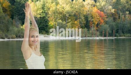 Digital composite of Double exposure of woman with hands clasped by lake against trees Stock Photo