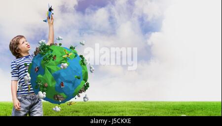 Digital composite of Boy playing with toy airplane with low poly earth in foreground Stock Photo