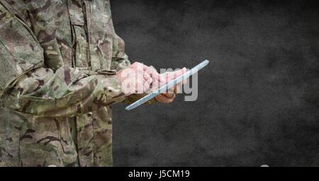 Digital composite of Soldier mid section with tablet and grunge overlay against grey wall Stock Photo