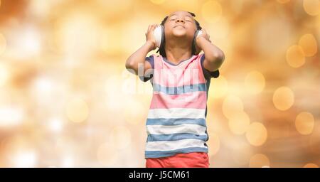 Digital composite of Boy listening music through headphones over bokeh Stock Photo
