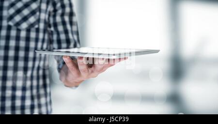 Digital composite of Man mid section with tablet behind bokeh against blurry grey window Stock Photo