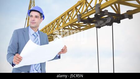 Digital composite of Male architect holding blueprint against crane Stock Photo