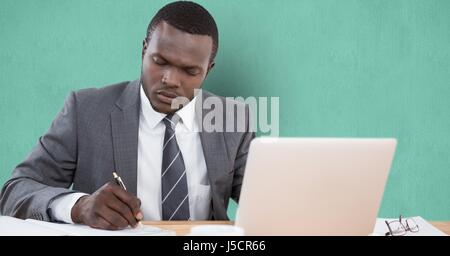 Digital composite of Businessman writing at desk over green background Stock Photo