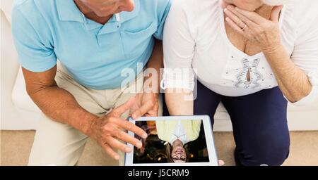 Digital composite of Senior couple video conferencing on tablet PC Stock Photo