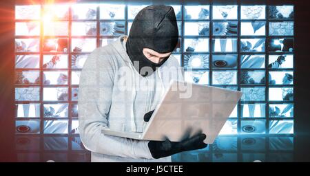 Digital composite of Hacker wearing monkey cap while using laptop Stock Photo