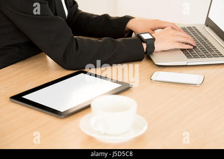 digital tablet computer displaying blank screen for copyspace near businesswoman connect with her smartwatch and laptop computer online working on the Stock Photo