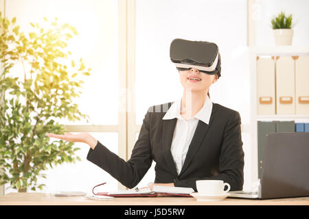 asian businesswoman presentation project by virtual reality on the air at the office with wearing VR headset glasses device over sunlight shine backgr Stock Photo