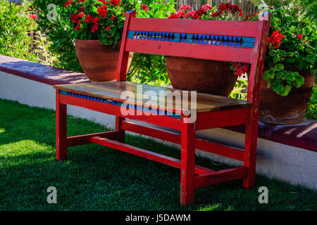 A colorful, hand crafted Mexican bench surrounded by a peaceful garden. Stock Photo