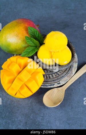 Mango ice cream sorbet with mint leaves and mango fruit in black stone bowl Stock Photo